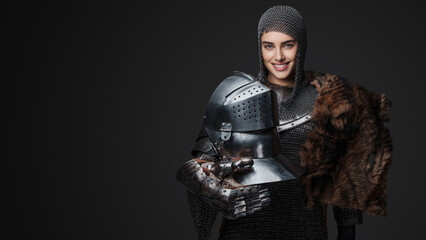 Beautiful female knight wearing medieval armor, smiling widely and confidently posing with a fur...