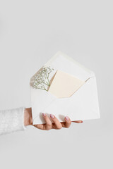 Woman holding envelope with blank invitation card and gypsophila flowers on white background