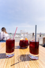 Two glasses of sangria and a pitcher on the table of a bar terrace with the blue sky background for copy space