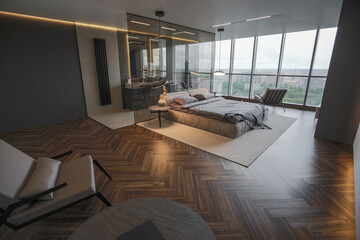 cool expensive interior design of room in prestigious luxury hotel with dark tones with modern LED lighting and stylish furniture. the area with a sink is separated by dark glass from the bedroom