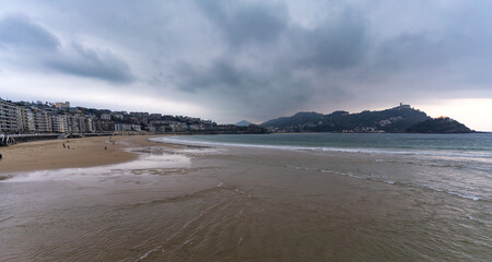 La Concha beach in San Sebastian with Mount Igueldo in the background. People walking on the sand