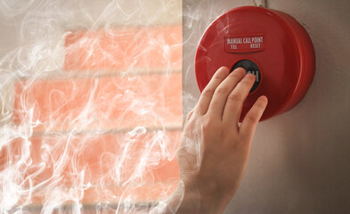 Foreman or worker pushing fire alarm on the wall. A fire! or Emergency case at the factory...