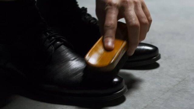 Waxing leather black classic shoes. Stock footage. Close up of cleaning and polishing boots.