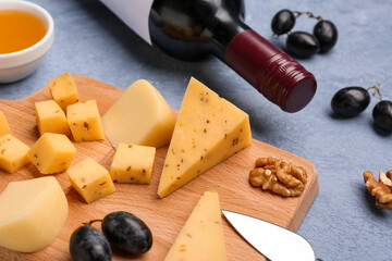 Wooden board with pieces of tasty cheese on grey background, closeup