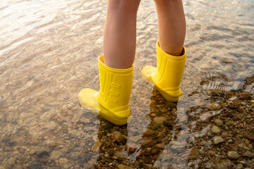 Woman legs in yellow rubber boots in the water