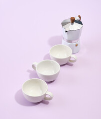 Three white ceramic cups and italian metallic coffee maker. Coffee break in office.