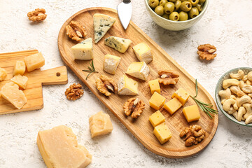Wooden board with pieces of tasty cheese on light background