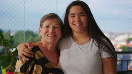 Joyful Generational Portrait_ Asian Diverse Granddaughter embracing by putting arm around and Kissing Caucasian Grandmother_s Cheek with Love