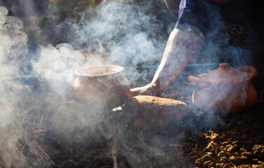 Cooking by using traditional clay pot  in dramatic light at camping