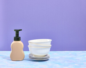 Set of white empty tableware. Plates different size. Copy space for text. Beige dispenser of dirty dishwashing detergent.