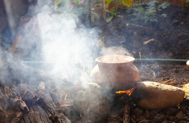 Cooking by using traditional clay pot  in dramatic light at camping