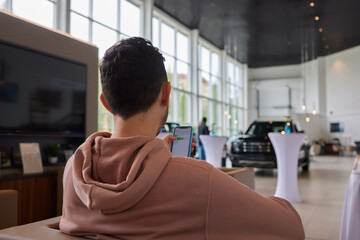 Smiling man in car dealership showroom sitting.