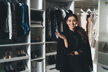 Smiling woman in elegant black outfit standing in wardrobe