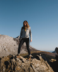 Tall young girl with long hair smiling standing on a rock in the mountains of Urkiola near Anboto...