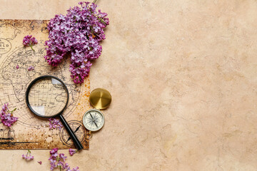 Fototapeta na wymiar World map with compass, magnifier and lilac flowers on beige grunge background
