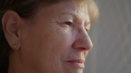 Fototapeta premium Close-up face of a pensive senior elderly woman with wrinkles. Older person in 70s in contemplation, thinking deeply about life and experience
