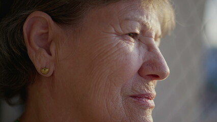 Close-up face of a pensive senior elderly woman with wrinkles. Older person in 70s in...