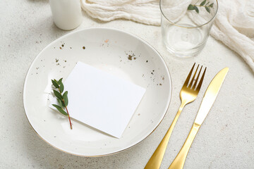 Plate with gold cutlery and blank card on white grunge background