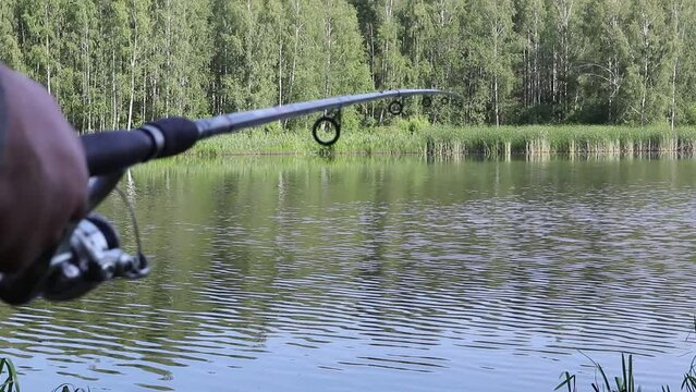 A fisherman with fishing rods, a spinning reel on the river bank. the lake has no focus. Sunrise. Fishing for pike, perch, carp. The concept of a country holiday.