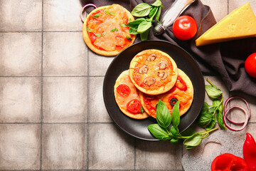 Plate with different tasty mini pizzas on grey tile background