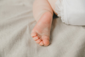 mom's hands hold the baby's legs in on a cotton bed, hygiene and care and care for the newborn.toddler's heel