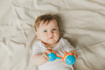A baby with a teether and a rattle on a cotton bed. Teething. Children's article. copy space