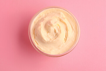 Bowl with tasty cream cheese on pink background