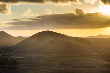 Naklejka premium Beautiful sun rays over El Cuervo Volcano in Lanzarote, Canary Islands, Spain