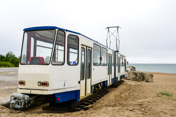 Obraz premium A used white electric tram car on the shore of the Baltic Sea for setting up a cafe, tram as a cafe