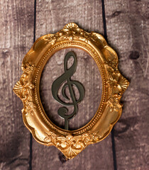musical note in a frame, vintage frame and a music note inside, concept, decoration, musical note in a frame on a wooden background