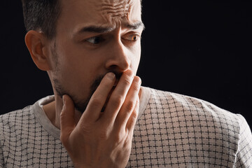 Young man having panic attack on black background, closeup