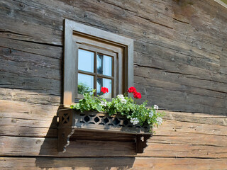 Fototapeta na wymiar Windows with flowers on a Bavarian house external wall