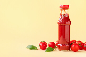 Glass bottle of ketchup and tomatoes on beige background