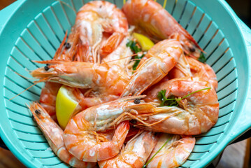Cooked cooked king prawns with lemon in colander. Top view.