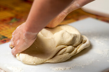 Fototapeta na wymiar Unrecognizable woman kneading dough. Dough for dumplings, dumplings, pies.