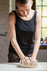 Bald woman kneading dough in kitchen. Making bread.