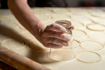 Fototapeta na wymiar Cooking dumplings, cutting circles from dough for modeling. Slovenian cuisine.