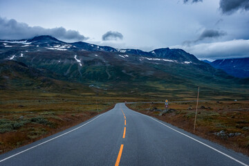 Empty road through the tundra of central Norway with cloudy and  moody sky