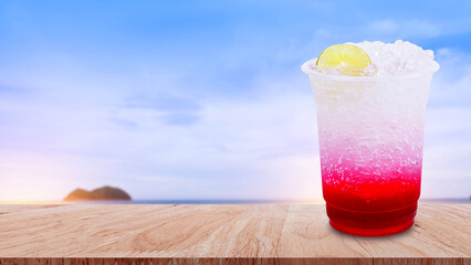 Italian soda made from fruit syrup drink mix in plastic cup on wooden table. Lemon, Red cocktail summer refreshment drink, Summer drinks with ice