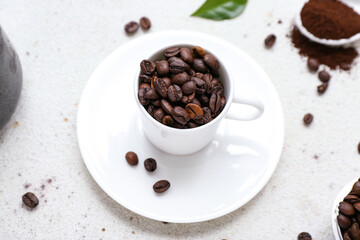 Cup with coffee beans on light background