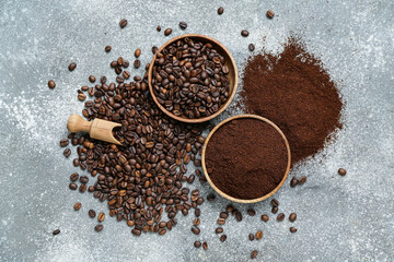 Bowls with coffee beans and powder on grey background