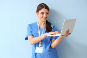 Female medical intern working with laptop on blue background