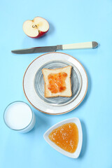 Plate of delicious toast with jam, milk and apple on color background