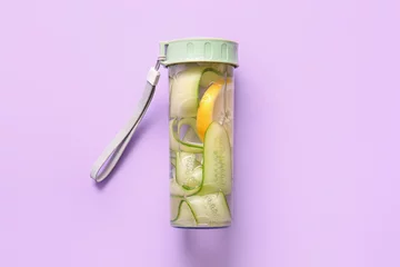 Keuken spatwand met foto Sports bottle of infused water with cucumber slices on lilac background © Pixel-Shot