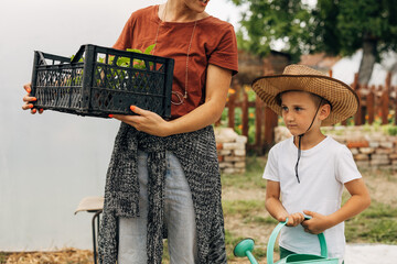 Cute young boy helps his mother with gardening.