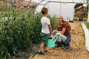Caucasian woman and her son are working together in their eco garden.