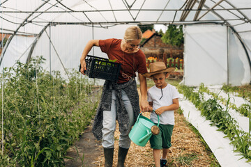 Mother and son are gardening together in the greenhouse.