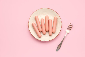 Plate with tasty thin sausages on pink background