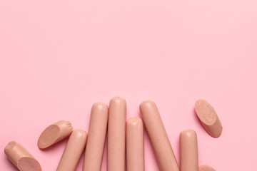 Tasty thin sausages on pink background