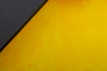 Yellow textured wall and metal black roof, copy space